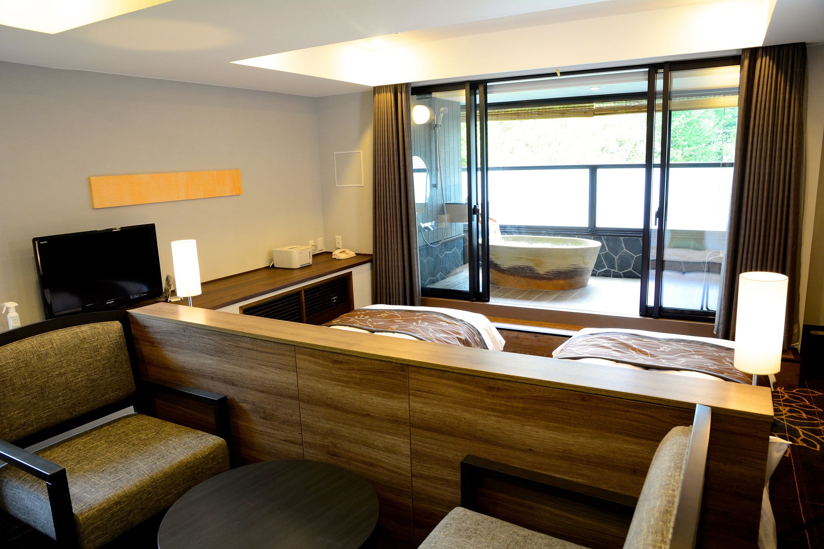 Habitación de hotel con cama, televisión, escritorio y ventana con cortinas.