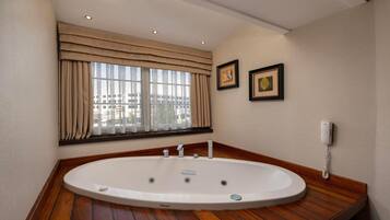 Un baño moderno con una bañera independiente, una ventana con cortinas, una obra de arte enmarcada y un teléfono.
