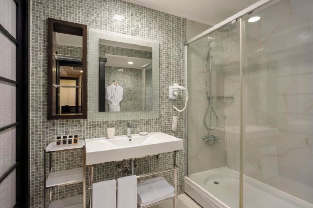 A bathroom with a glass-enclosed shower, a white sink, and a mirror above it.