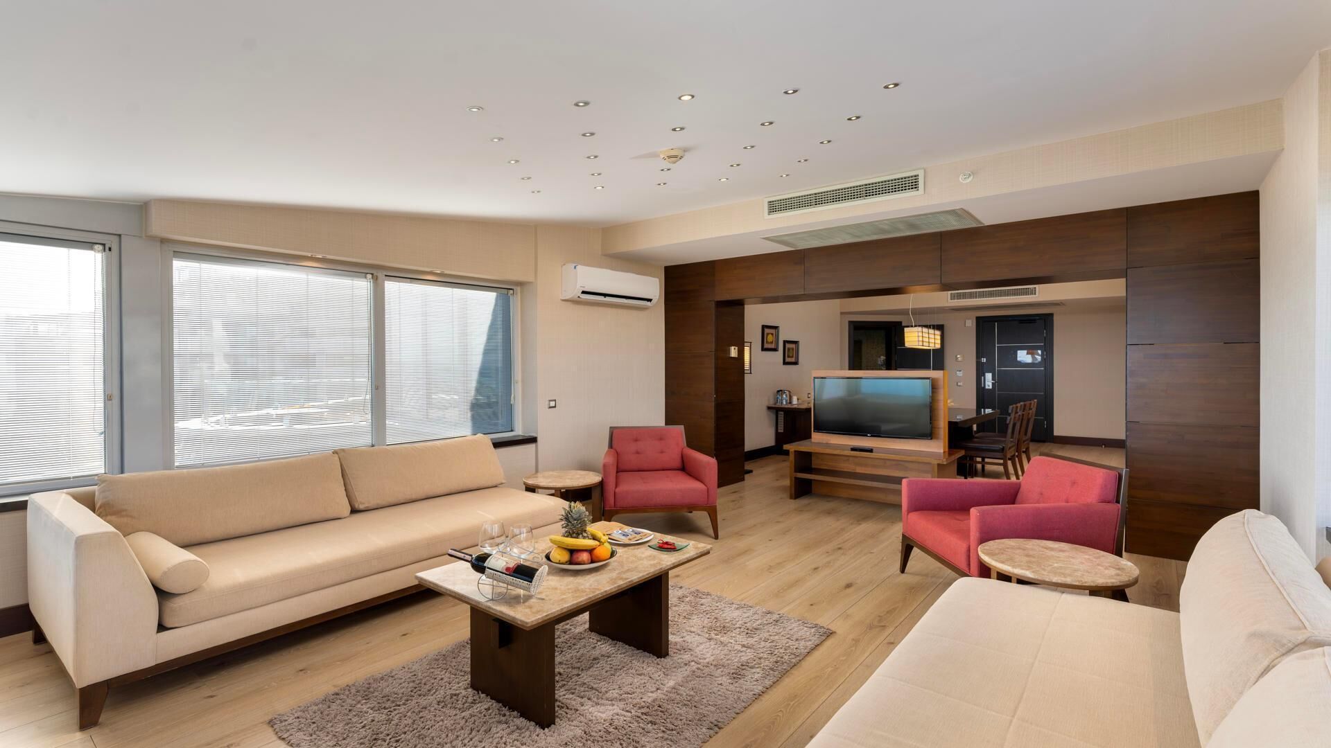 Un salon moderne comprenant un canapé, deux fauteuils, une table basse et un espace dédié à la télévision.