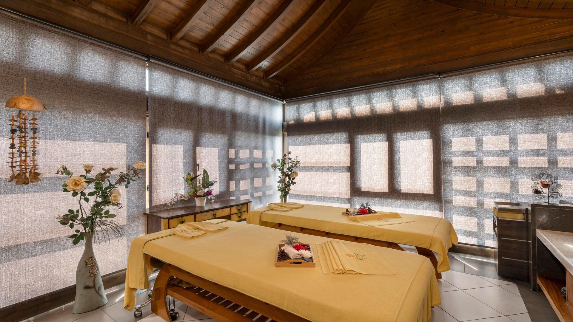 Ein Zimmer mit zwei Betten, einer Holzbalkendecke und einem großen Fenster mit Blick.
