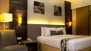 Een hotelkamer met een bed, een stoel, nachtkastjes en wandlampen.