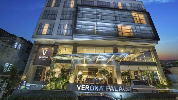 Een modern hotel met een opvallende ingang, grote ramen en een bord waarop 'VERONA PALACE' staat.