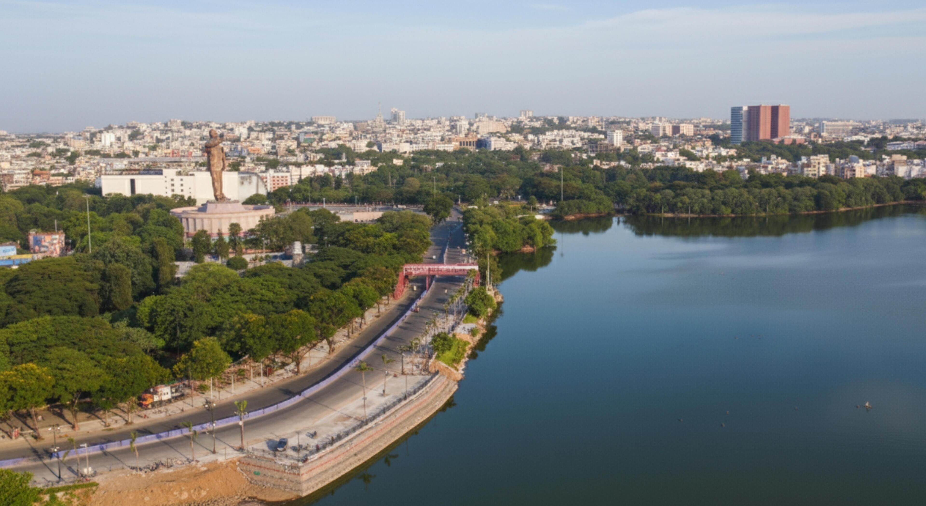 A riverside view of a city with a bridge, buildings, and greenery.