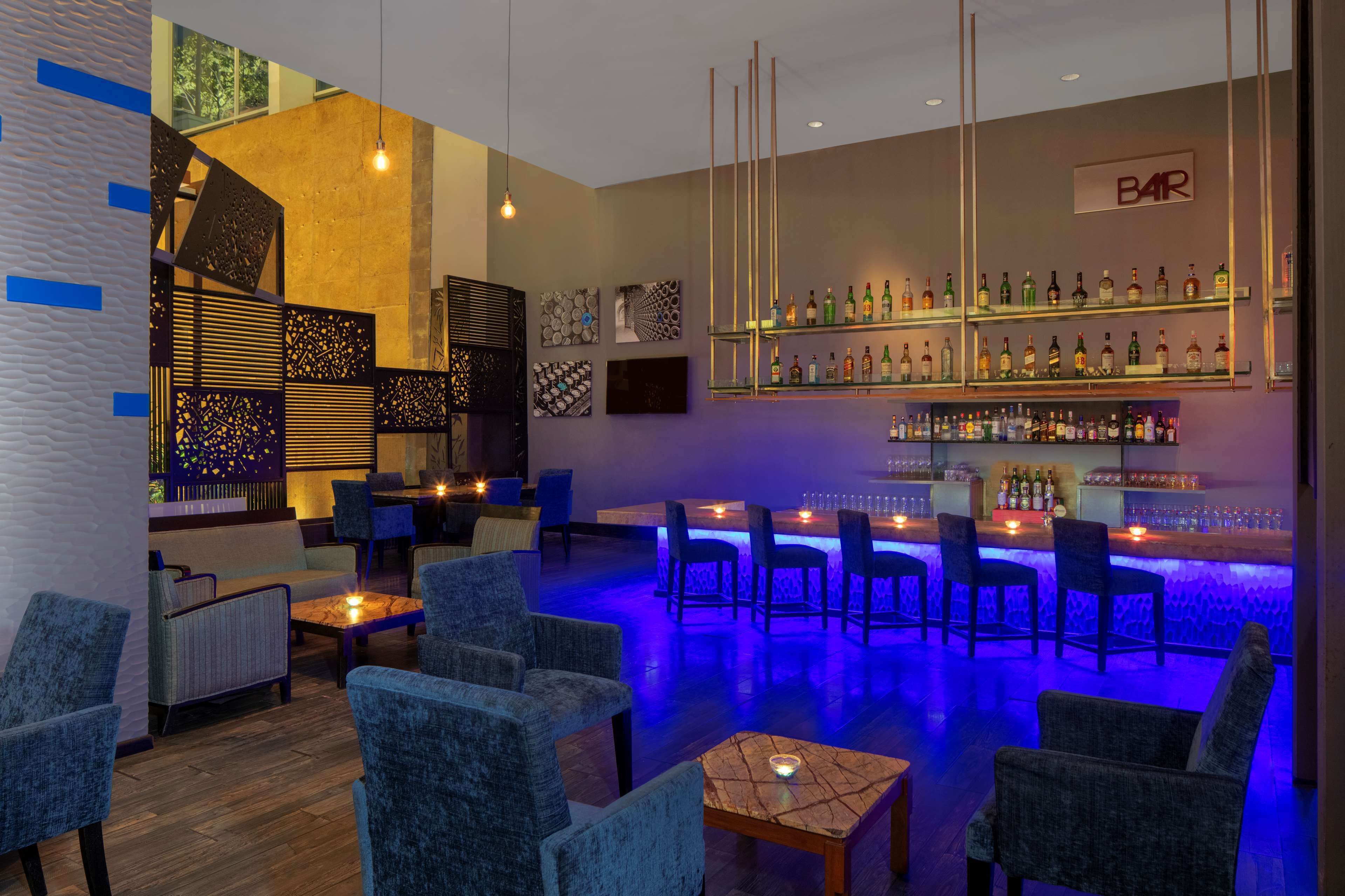 Zona de bar con diversas opciones de asiento, barra bien surtida y decoración en las paredes.