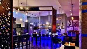 A modern bar area with a bar counter, seating, and a variety of bottles. - Radisson Blu Plaza Hotel Hyderabad Banjara Hills (Hyderabad)