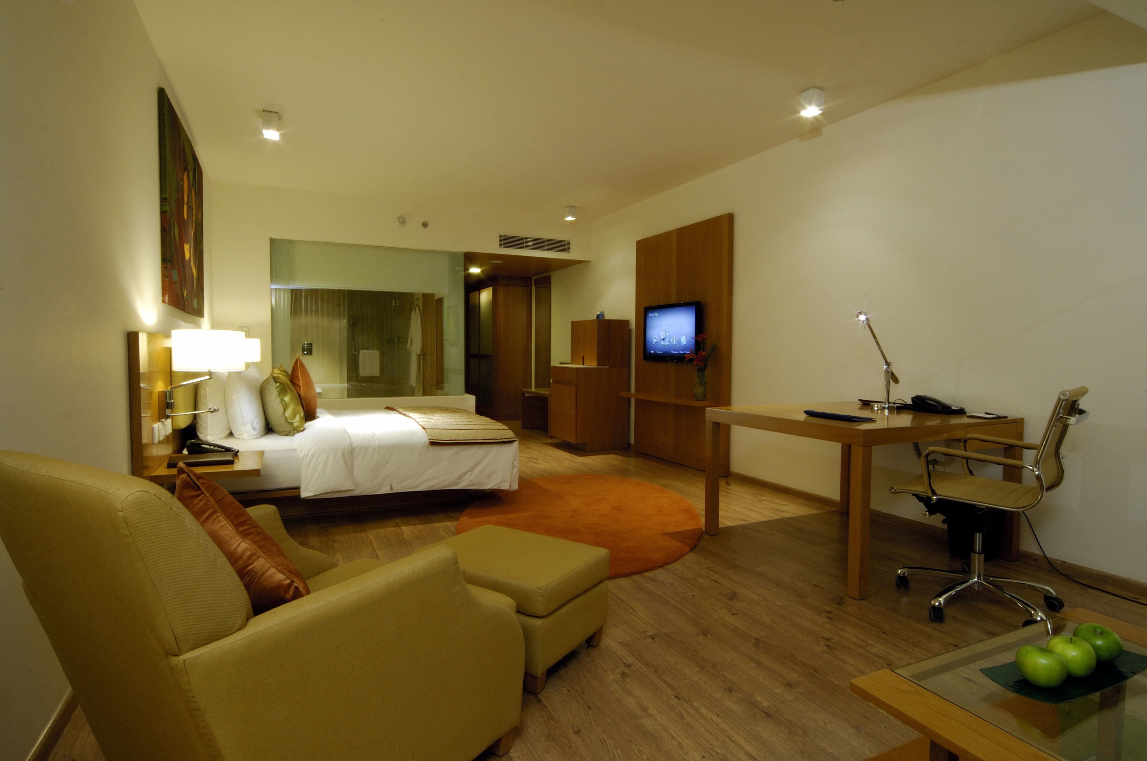 A hotel room with a bed, a desk, a chair, a sofa, and a television.