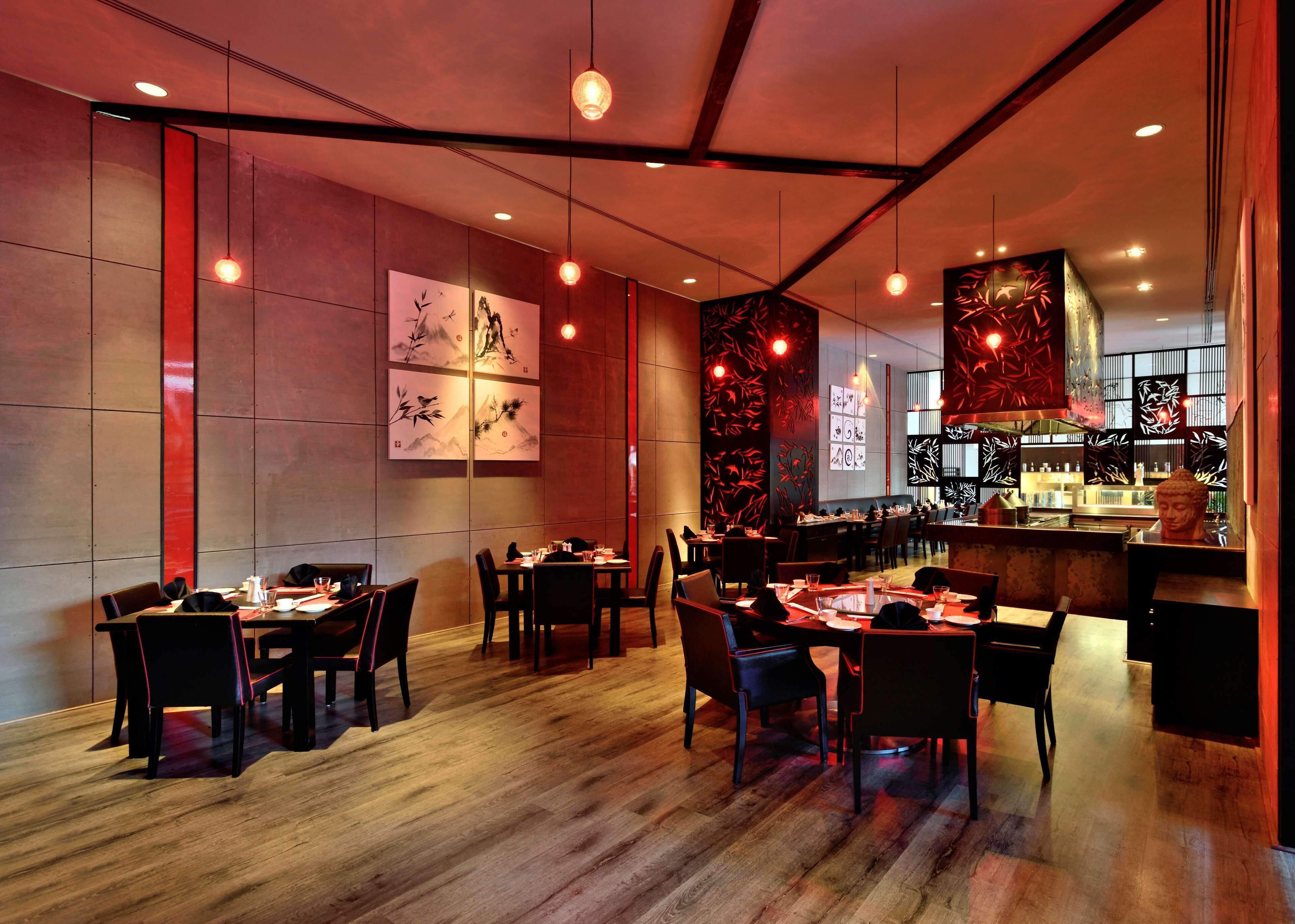 Un interior de restaurante con suelo de madera, mesas dispuestas para comer y obras de arte en las paredes.