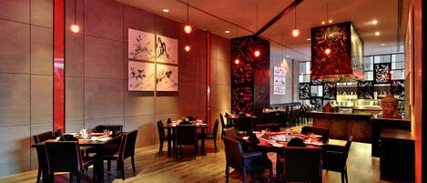 A restaurant interior with wooden flooring, tables set for dining, and artwork on the walls.