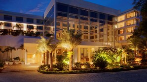 A modern hotel with a glass facade, multiple floors, and a well-lit entrance. - Radisson Blu Plaza Hotel Hyderabad Banjara Hills (Hyderabad)