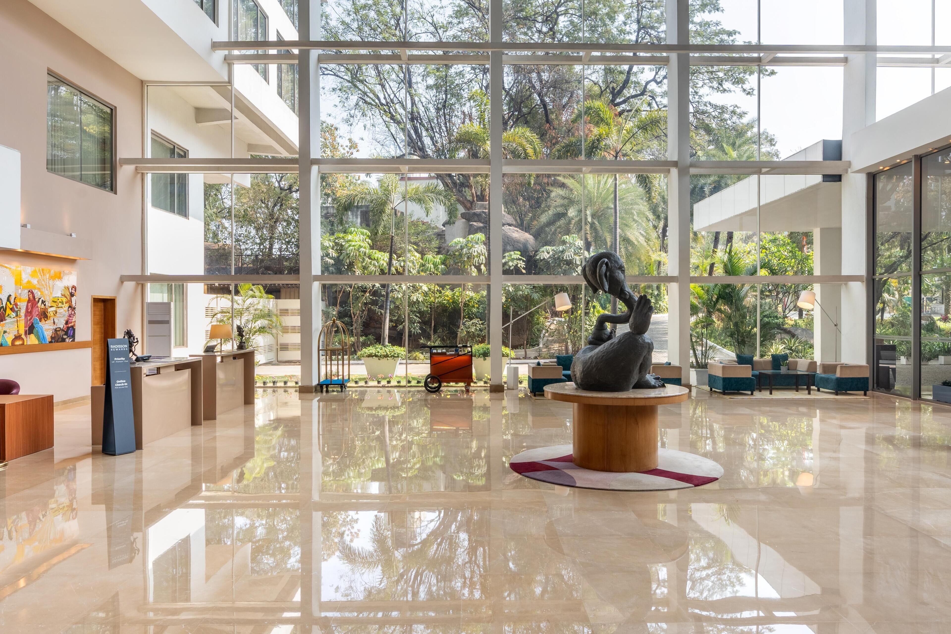 Un vestíbulo espacioso con techo alto, ventanas amplias y una escultura central.