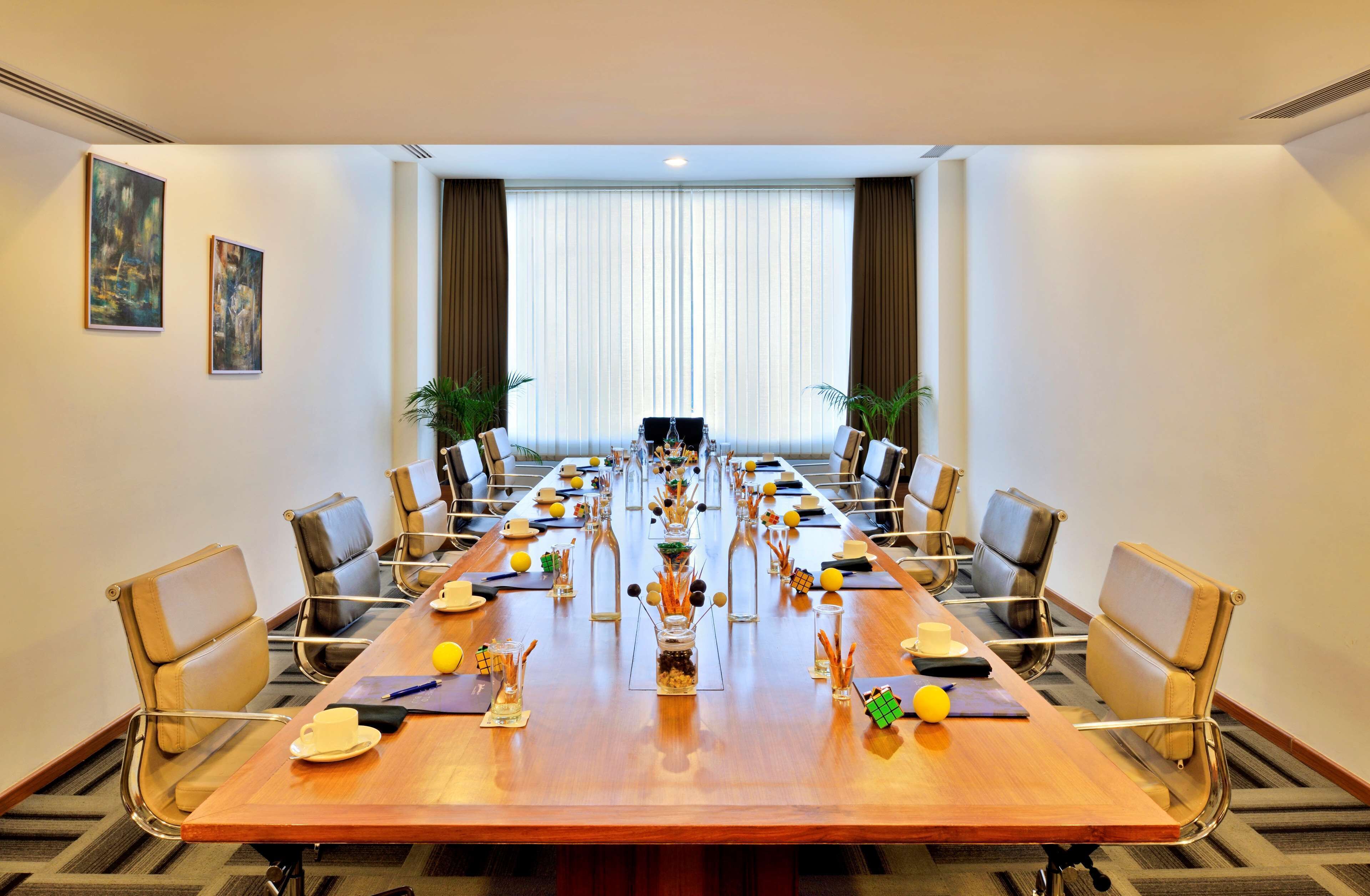 A conference room with a long table, chairs, and a large window with curtains.