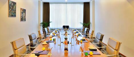 A conference room with a long table, chairs, and a large window with curtains.