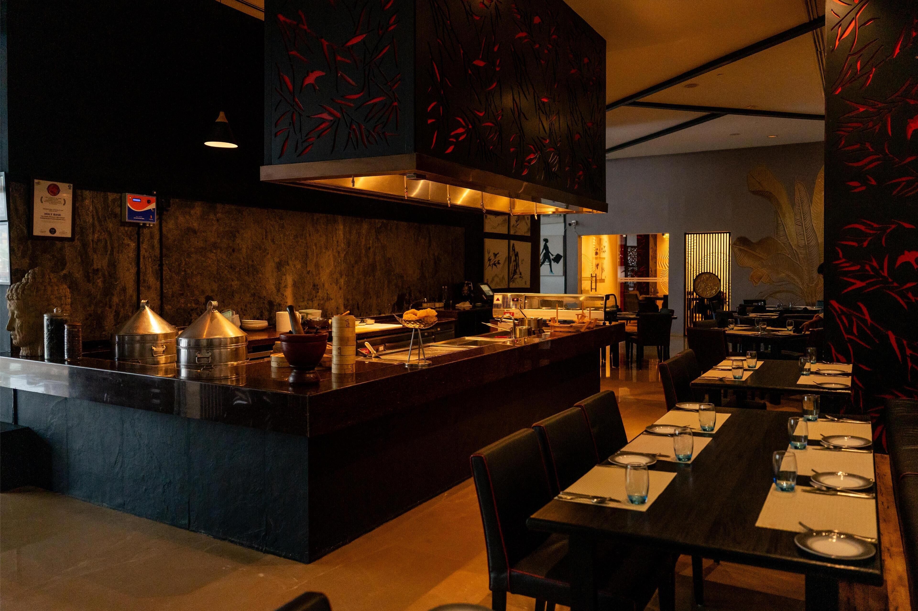 Um restaurante com balcão central, mesas e cadeiras.