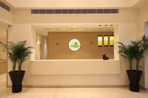 A reception area with a large, circular stained glass window, two potted plants, and a reception desk.