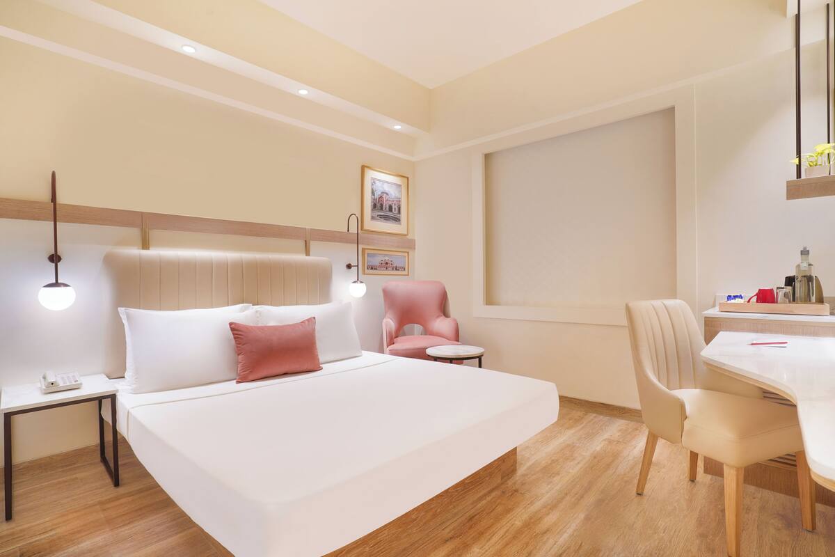 Ein Hotelzimmer mit einem großen Bett, einem Schreibtisch, einem Stuhl und einem kleinen Tisch.