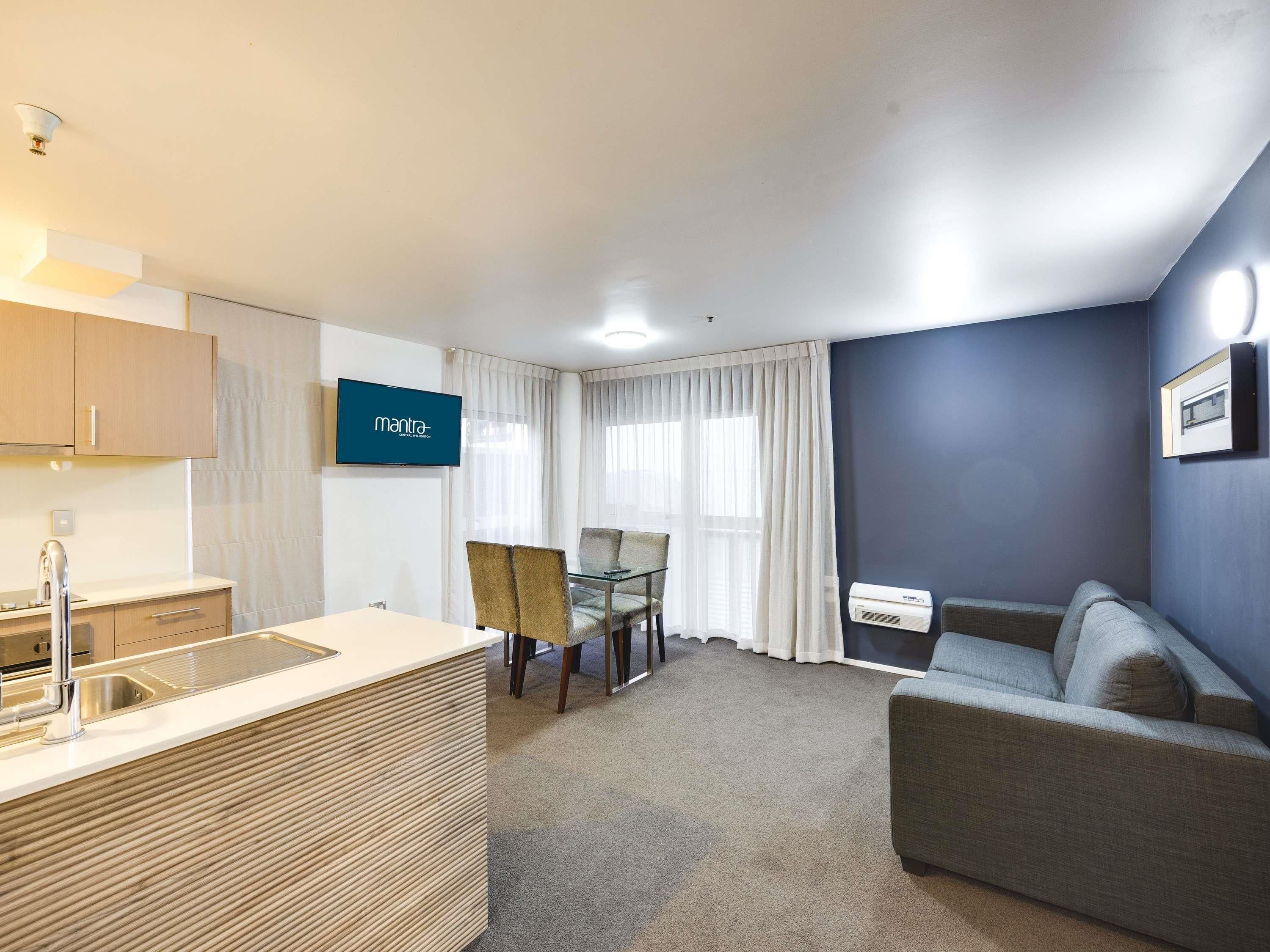 Una habitación de hotel moderna con kitchenette, zona de comedor y sala de estar.