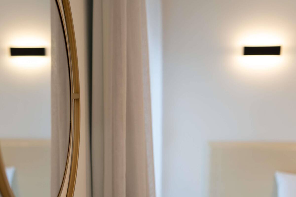 Ein Hotelzimmer mit einem großen Spiegel, einem Bett mit Kopfteil und zwei Wandleuchten.