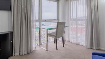 A room with a large window, a chair, a TV, and a blue sofa.