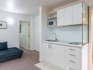 A compact kitchenette with a microwave, sink, and cabinets. - Mantra Central Wellington  (Wellington)