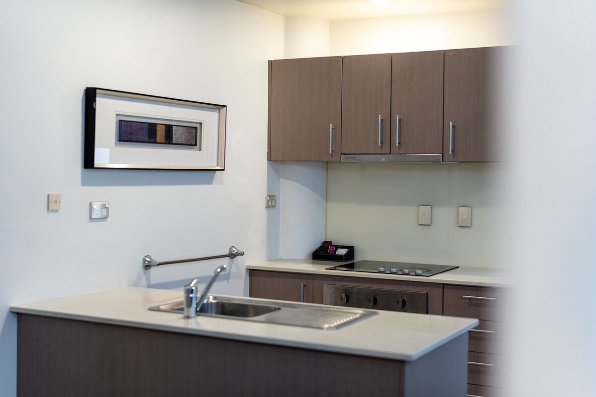 A modern kitchen with a stainless steel sink, a microwave, and wooden cabinets.