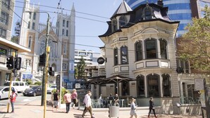 A historic building with a distinctive corner turret and large windows.