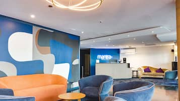 A modern lobby with a reception desk, seating area, and abstract wall art.