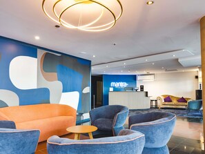 A modern lobby with a reception desk, seating area, and abstract wall art. - Mantra Central Wellington  (Wellington)