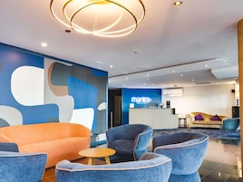 A modern lobby with a reception desk, seating area, and abstract wall art.