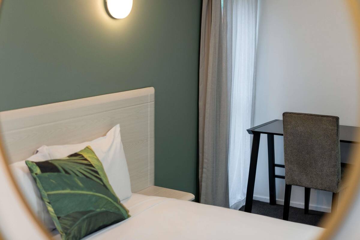 A hotel room with a bed, a desk, and a chair.