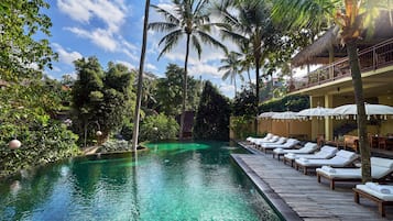 Una piscina al aire libre, sombrillas, sillones reclinables de piscina