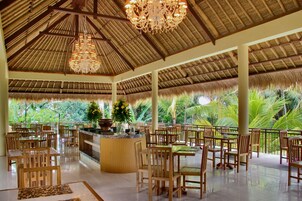 A spacious indoor area with a high ceiling, wooden furniture, and a central island with a plant.