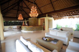 A spacious lobby with a high ceiling, a central stone feature, and white sofas.