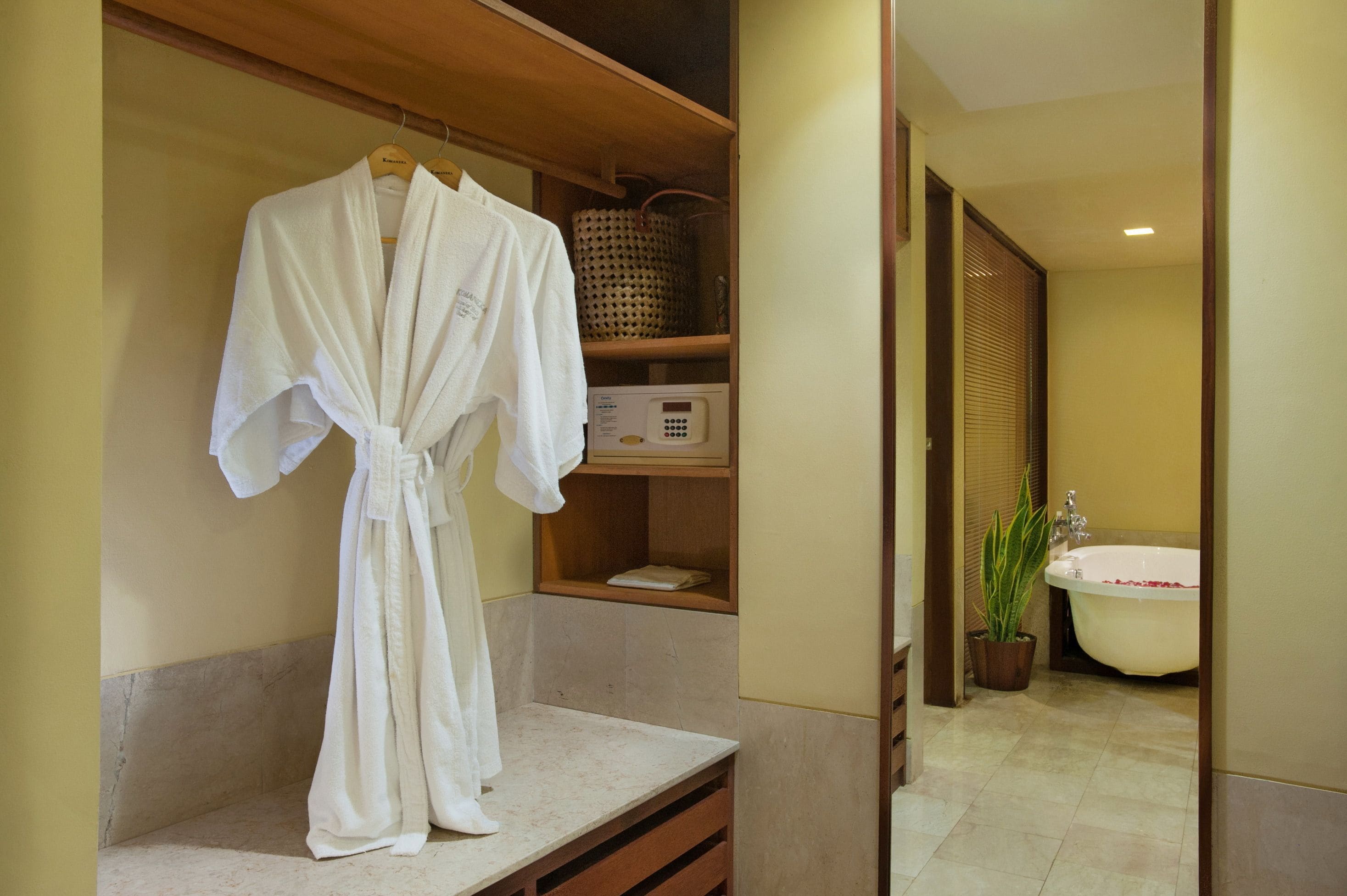 A bathroom with a bathtub, a sink, a mirror, and a robe hanging on a rack.