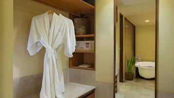 A bathroom with a bathtub, a sink, a mirror, and a robe hanging on a rack.
