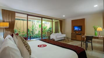 A hotel room with a large bed, a sofa, a desk, and a TV.