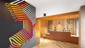 A reception area with a modern design, featuring a wooden reception desk, a large abstract wall art piece, and a herringbone patterned floor. - Ginger Mumbai Andheri (MIDC) (Mumbai)