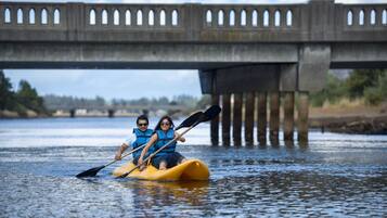 Deux personnes pratiquent le kayak sur une rivière, sous un pont.