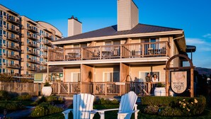 A two-story building with balconies, a sign reading "Inn at the Prom", and two white Adirondack chairs in the foreground. - Inn at the Prom Oceanfront Seaside (Seaside)