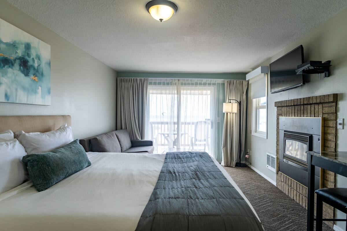 Ein Hotelzimmer mit einem großen Bett, einer Couch, einem an der Wand montierten Fernseher und einem Kamin.