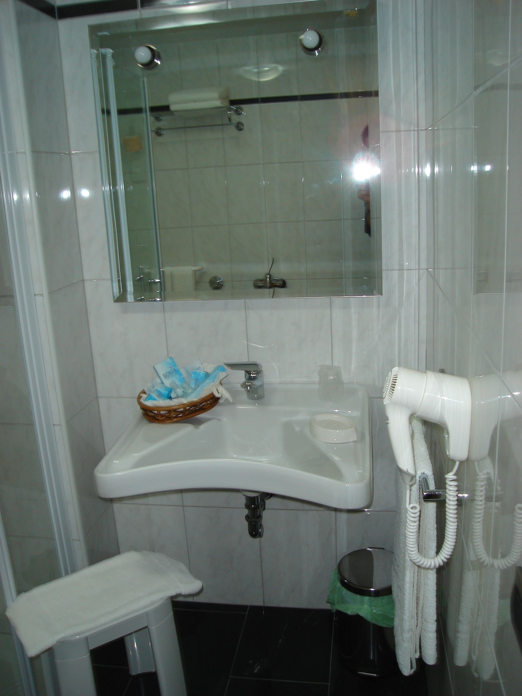 Une salle de bain équipée d’un lavabo, d’un miroir, d’une douche et d’un sèche-cheveux.