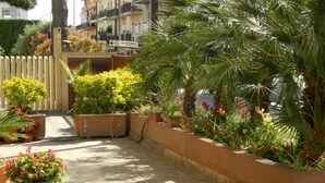 A courtyard with potted plants, a wooden fence, and a sign for the Palace Hotel. - Hotel Le Palme (Gioia Tauro)