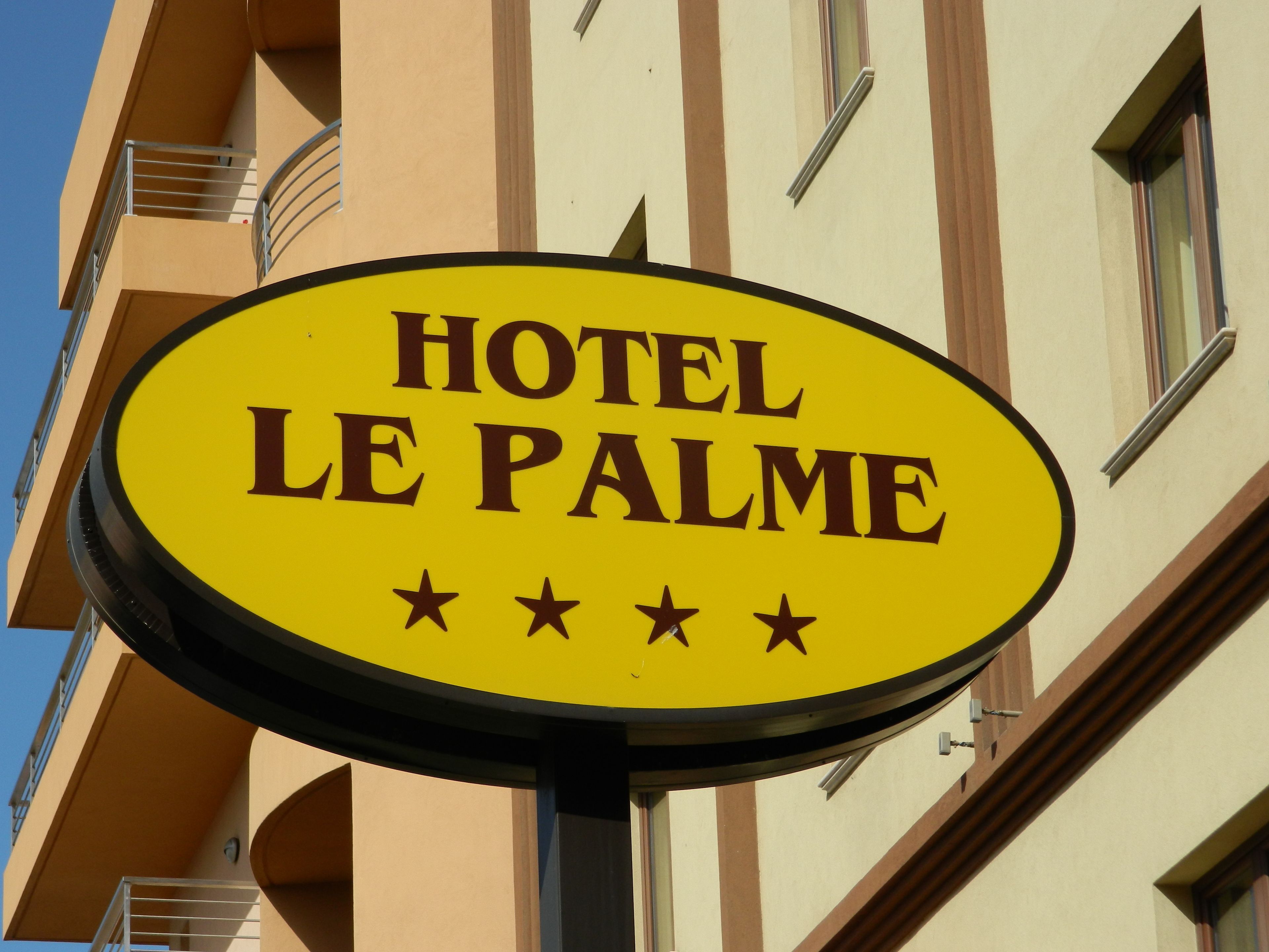 Segnaletica gialla con su scritto "HOTEL LE PALME" e tre stelle.