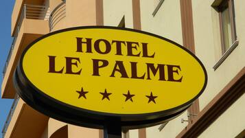 Un letrero amarillo que dice "HOTEL LE PALME" y muestra tres estrellas.