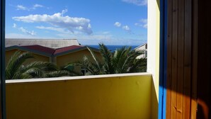 A balcony with a view of the sea and buildings. - Hotel Alexander (Ricadi)