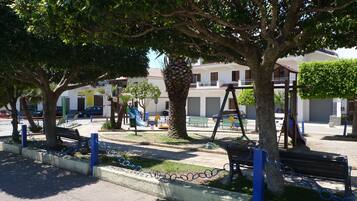 Un parco con panchine, giochi per bambini e alberi.