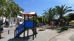 A playground with a climbing structure, a slide, and a swing set. - Hotel Alexander (Ricadi)