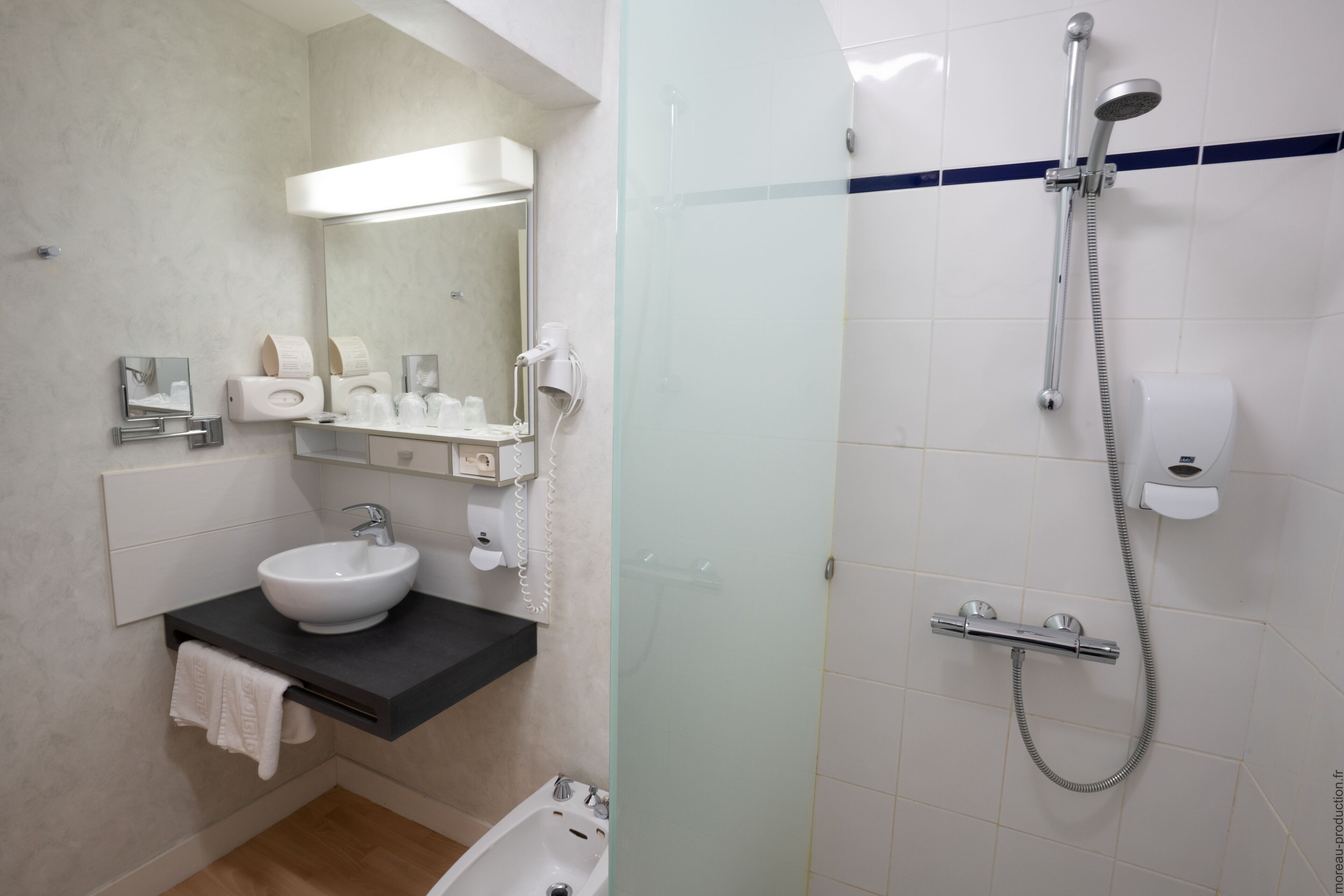 Een moderne badkamer met een wastafel, spiegel en douche.