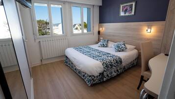 Ein Schlafzimmer mit einem Bett, einem Sessel, einem Fenster und einer Wandleuchte.