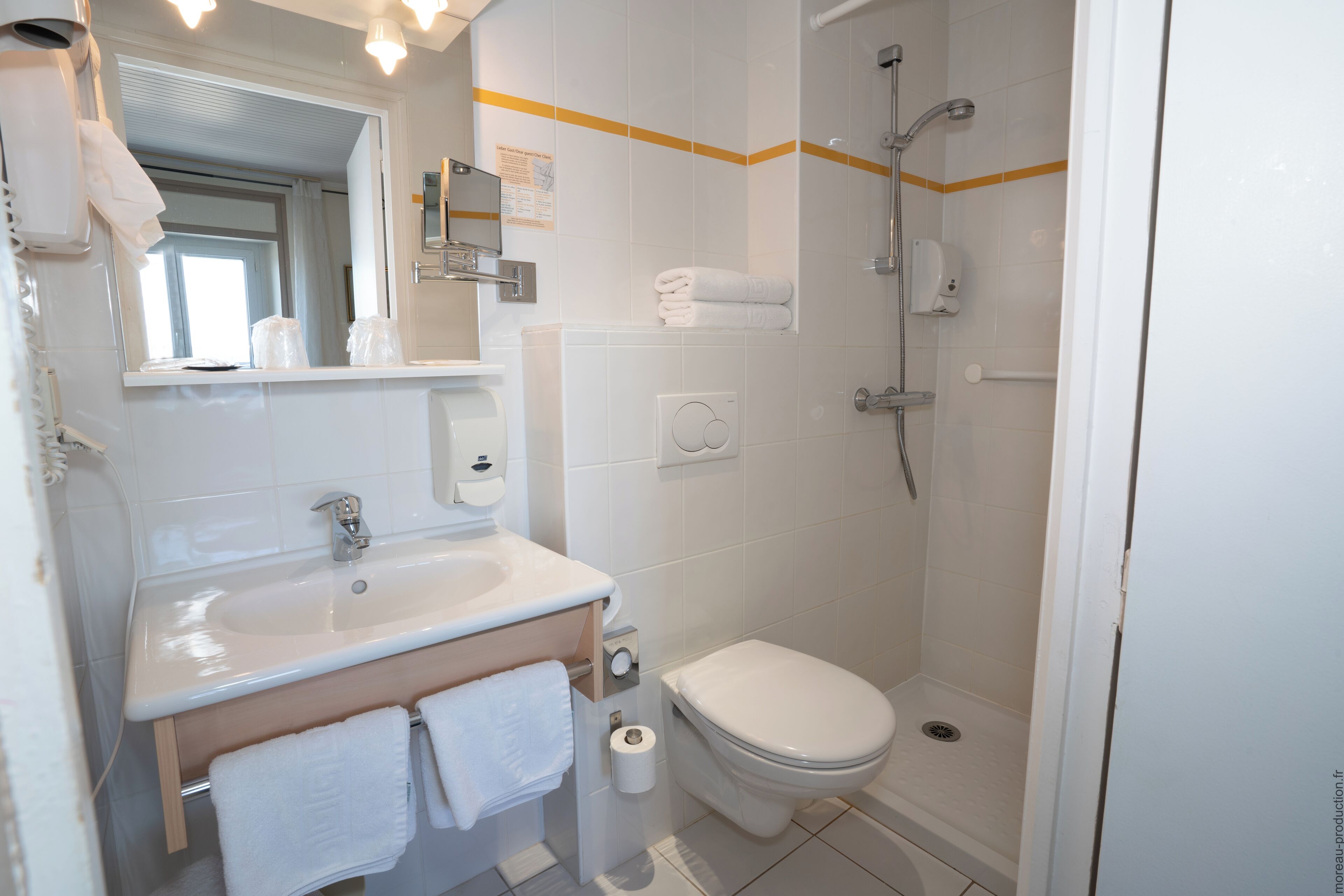 Une salle de bain moderne équipée d’un lavabo, de toilettes et d’une douche.